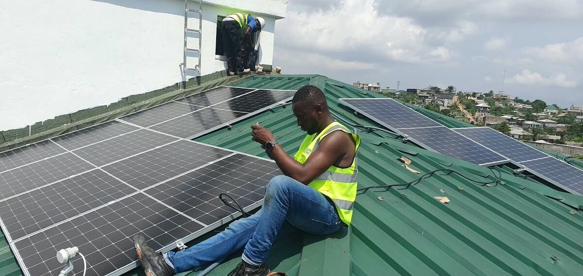 Technicien Cameroun Energy sur une toiture équipée de panneaux solaires